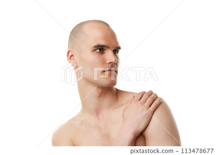 Young shirtless man with bald head, shaved face taking care after skin in bathroom isolated on white studio background 113478677