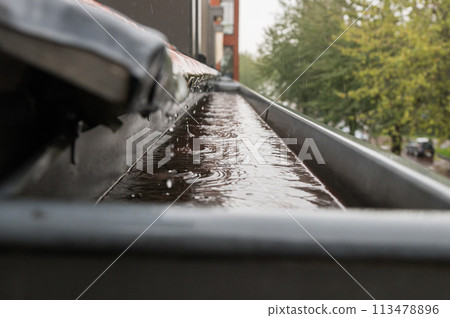 Rain flows down the roof into the drain pipe Rain flows down the roof into the drain pipe 113478896