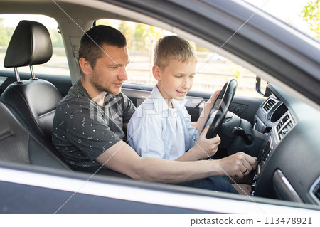 Dad shows his son how to drive a car. The child is driving with dad 113478921