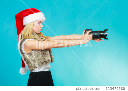 Photographer girl in santa claus hat shooting images 113479380