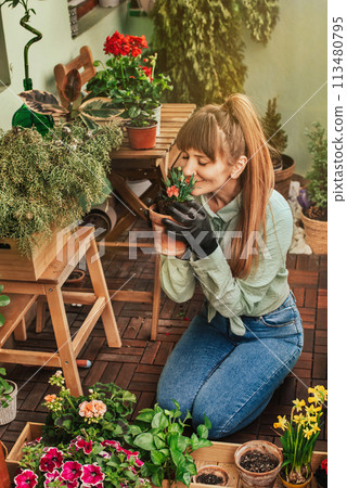 Young Woman Gardener Kneeling on Apartment Balcony 113480795