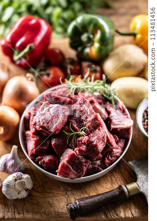 Pieces of chopped beef in a bowl with vegetables, ready for goulash 113481456