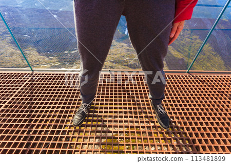 Tourist feet on Dalsnibba platform floor, Norway Tourist feet on Dalsnibba platform floor, Norway 113481899
