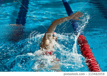 Dynamic image of young man, swimmer in cap and goggles in action, motion, swimming freestyle stroke in pool. Dynamic image of young man, swimmer in cap and goggles in action, motion, swimming freestyle stroke in pool. 113482059
