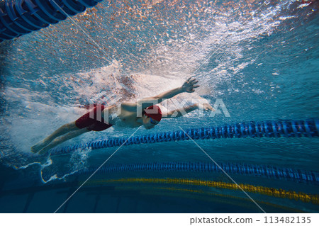 Beauty of athleticism in action. Dynamic image of young man, athlete in motion, swimming in s pool indoors, training Beauty of athleticism in action. Dynamic image of young man, athlete in motion, swimming in s pool indoors, training 113482135