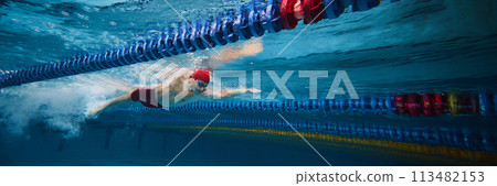 Young concentrated man, swimming athlete in motion in swimming pool training, preparing for upcoming competition 113482153