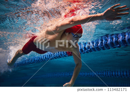 Freestyle swimming type. Dynamic image of yo9ung male athlete, swimmer in motion, training in swimming pool. Underwater 113482171
