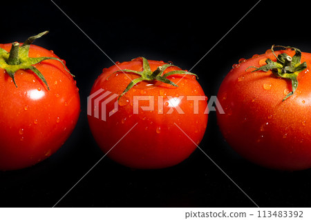 Fresh tomatoes with water drops on a black background close-up 113483392