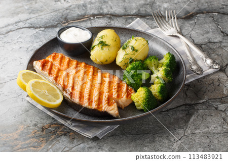 Grilled salmon, boiled potatoes, broccoli and cream sauce in a plate. Horizontal Grilled salmon, boiled potatoes, broccoli and cream sauce in a plate. Horizontal 113483921