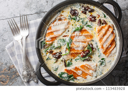 Creamy Tuscan Salmon is a simple but very richly flavoured dish with creamy garlic sauce sun-dried tomato and spinach closeup in the pan. Horizontal top view Creamy Tuscan Salmon is a simple but very richly flavoured dish with creamy garlic sauce sun-dried tomato and spinach closeup in the pan. Horizontal top view 113483928