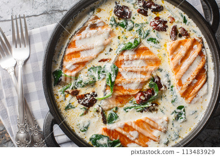 Marry Me Salmon smothered in a buttery, creamy sun-dried tomato spinach sauce closeup in the pan. Horizontal top view Marry Me Salmon smothered in a buttery, creamy sun-dried tomato spinach sauce closeup in the pan. Horizontal top view 113483929