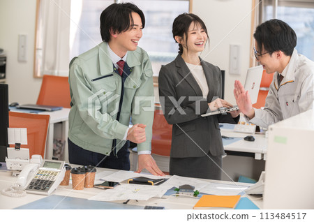 Three male and female engineers having a meeting in an office Three male and female engineers having a meeting in an office 113484517