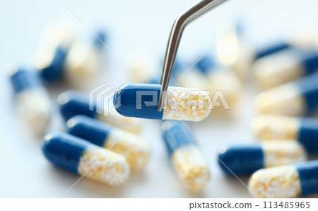 Arm lifting up pill with tweezers closeup 113485965
