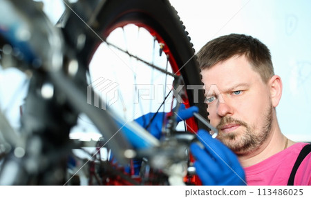 Male repair man bicycle service in blue protective Male repair man bicycle service in blue protective 113486025