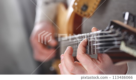Male arms playing classic shape electric guitar Male arms playing classic shape electric guitar 113486066