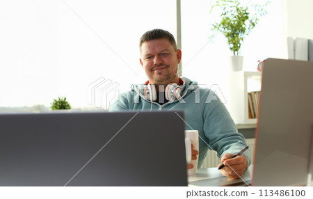 Handsome smiling male student using online Handsome smiling male student using online 113486100