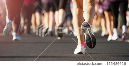 Marathon running in the light of morning. People feet on city road 113486616