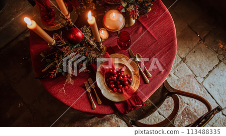 Festive table setting  with cutlery, candles and beautiful red flowers in vase 113488335