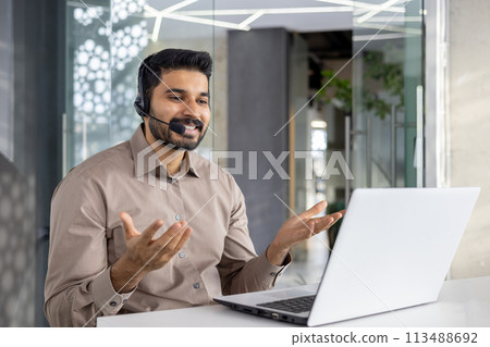 A cheerful customer service representative talks using headset in a modern office setting, assisting clients with expertise and a smile 113488692