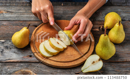 Woman Cutting a Pear into Thin Slices on a Wooden Cutting Board - Generative Ai 113488750