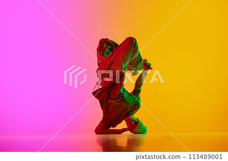 Creative, dynamic photo of breakdance performing freezes in neon light against gradient pink-yellow background. Creative, dynamic photo of breakdance performing freezes in neon light against gradient pink-yellow background. 113489001
