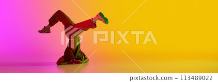 Banner. Young man, break-dancer stands on head in neon light against gradient pink-yellow background with negative space to insert text. Banner. Young man, break-dancer stands on head in neon light against gradient pink-yellow background with negative space to insert text. 113489022