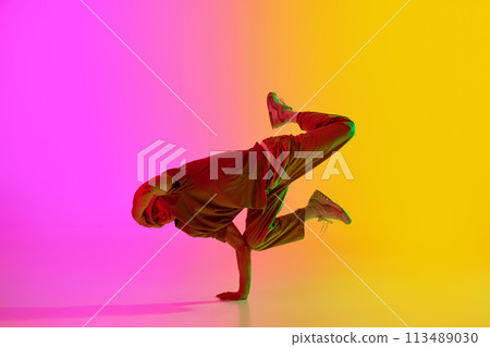 Dynamic photo of contemporary dancer dancing in freestyle in neon light against gradient pink-yellow background. 113489030