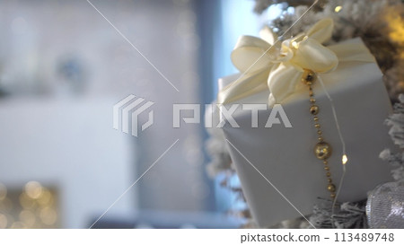 A white box with a gold ribbon hanging from it. Concept of joy and celebration, as the box is likely a gift for a special occasion. A white box with a gold ribbon hanging from it. Concept of joy and celebration, as the box is likely a gift for a special occasion. 113489748