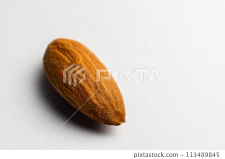 Almonds on a white background, close-up of the seed from the side. One nut macro shot Almonds on a white background, close-up of the seed from the side. One nut macro shot 113489845