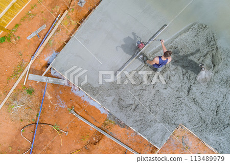 Use of special tools by construction worker in leveling concrete 113489979
