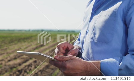 Businessman digital agricultural farmer with tablet. Hands holds gadget tablet. Regulation of agricultural production issues study of new technologies methods of soil plant care doing business online. 113491515