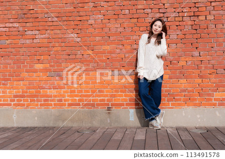 A woman standing in front of a brick wall A woman standing in front of a brick wall 113491578