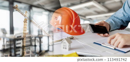 A builder is working in an office on a house project . 113491742