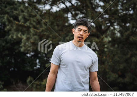 A man in his 40s doing strength training with dumbbells in the park 113497007