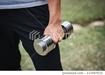 一名 40 多歲的男子在公園裡用啞鈴進行肌力訓練 一名 40 多歲的男子在公園裡用啞鈴進行肌力訓練 113497010
