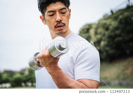 Man doing exercises with dumbbells outdoors 113497213