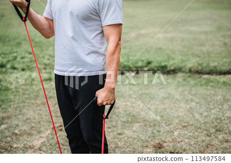 一名 40 多歲的男子在公園裡用訓練管進行肌肉訓練 一名 40 多歲的男子在公園裡用訓練管進行肌肉訓練 113497584