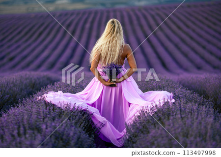 Back view woman lavender sunset. Happy woman in pink dress holds lavender bouquet. Aromatherapy concept, lavender oil, photo session in lavender 113497998