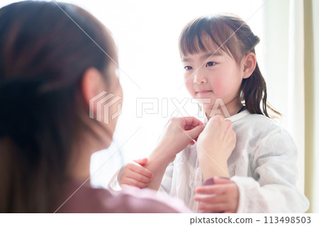 Mother helping little girl change clothes 113498503