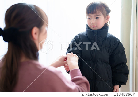 Mother helping little girl change clothes Mother helping little girl change clothes 113498667