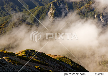 The ridgeline and flowing clouds in the evening sun as seen from Mount Senjo in the Southern Alps The ridgeline and flowing clouds in the evening sun as seen from Mount Senjo in the Southern Alps 113498900