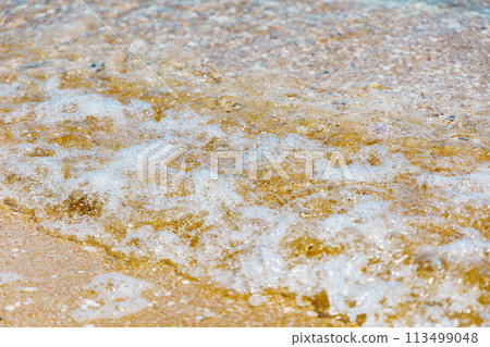 Gentle waves crashing on the sandy beach 113499048
