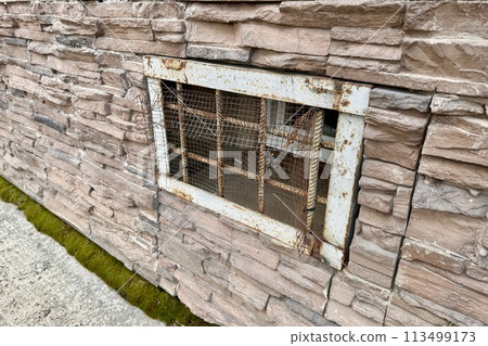 Abandoned warehouse window. Rusty grate window. Safety security protection. Light brick wall with metal grate window cover. Basement background Abandoned warehouse window. Rusty grate window. Safety security protection. Light brick wall with metal grate window cover. Basement background 113499173