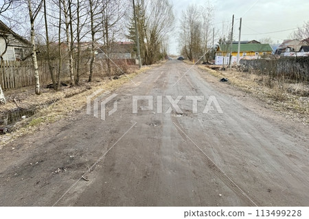 An old dirt village road stretches along an abandoned village during daylight hours An old dirt village road stretches along an abandoned village during daylight hours 113499228