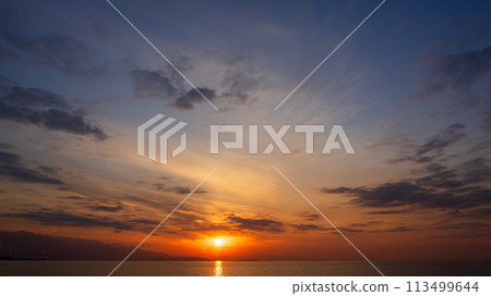 夕陽在傍晚的天空和許多雲彩中落下 113499644