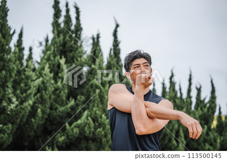 一名40多歲的男子在公園裡做熱身運動 一名40多歲的男子在公園裡做熱身運動 113500145