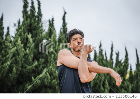 A man in his 40s doing warm-up exercises in the park 113500146
