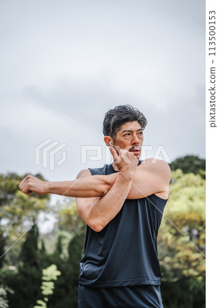 A man in his 40s doing warm-up exercises in the park 113500153