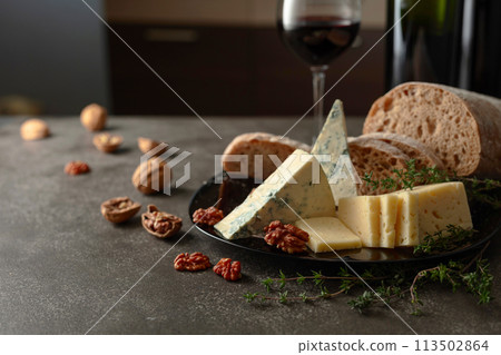 Cheese, bread, red wine, and walnuts on a kitchen table. 113502864
