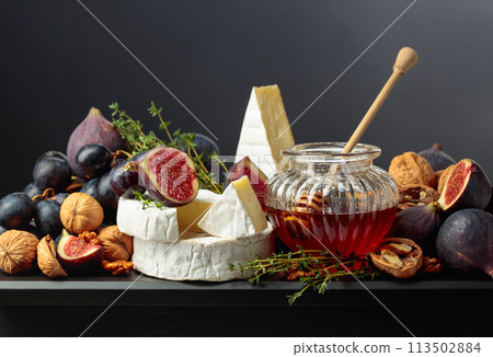 Camembert cheese with fruits and honey on a black background. Camembert cheese with fruits and honey on a black background. 113502884